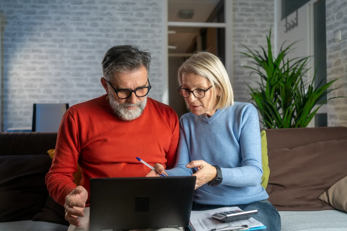Hand holding house keys in front of a home